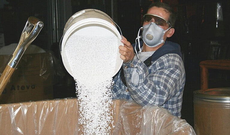 Worker wearing an N95 Respirator while dumping material into a storage bin